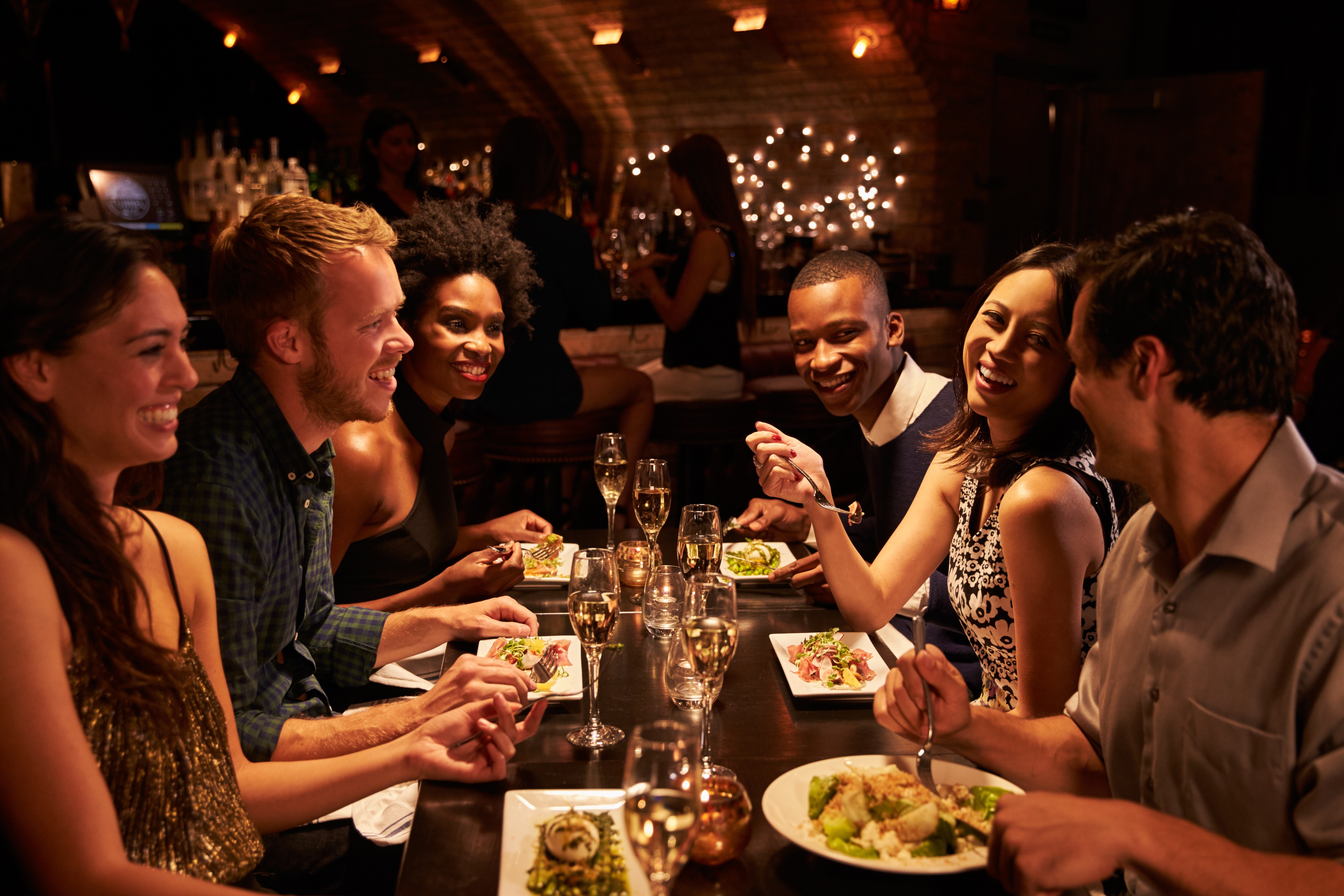 AI for restaurants — guests enjoying wine and dinner together at a candlelit restaurant table